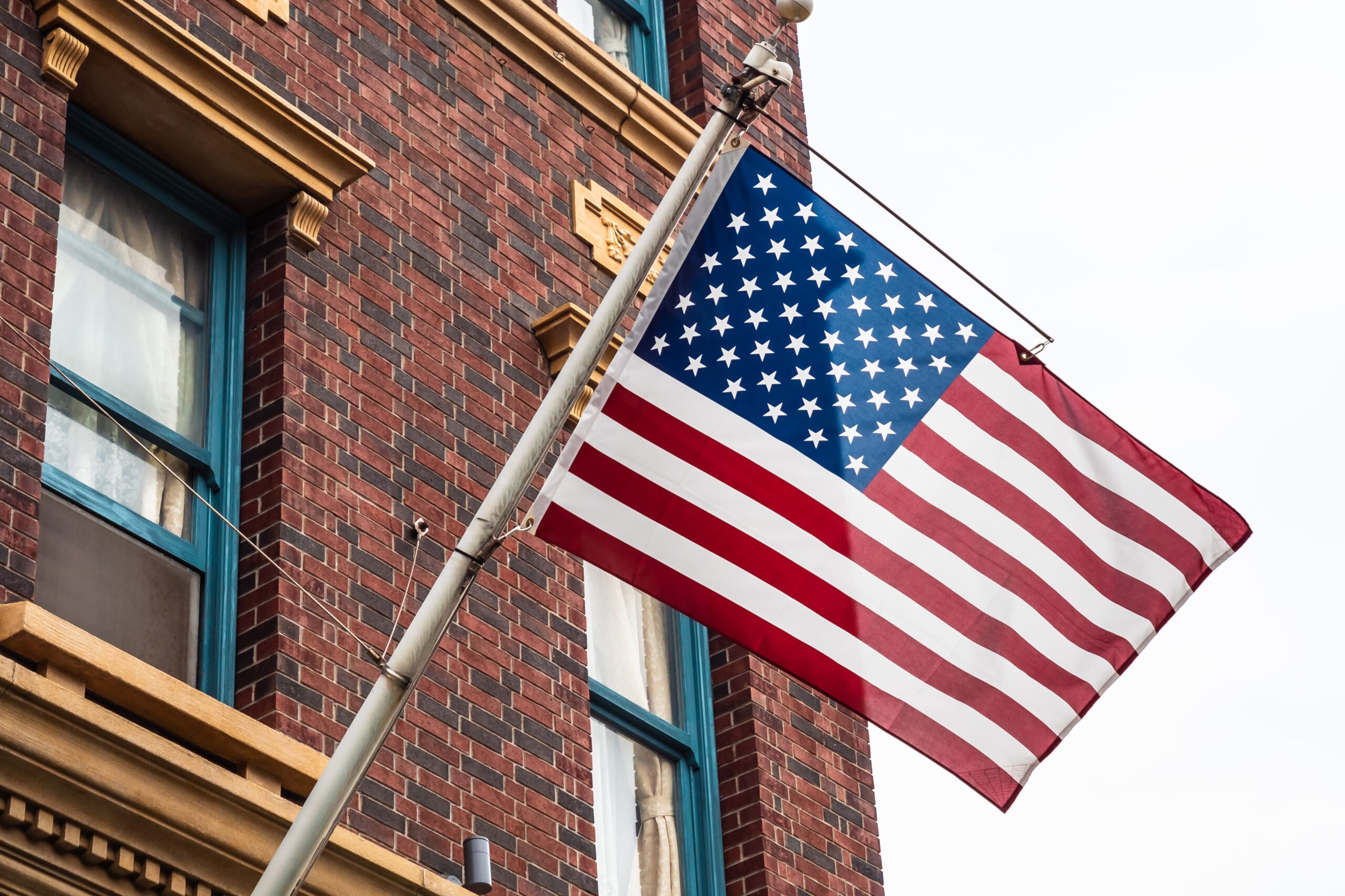 Bandeira dos Estados Unidos em frente ao um prédio de tijolod marrons